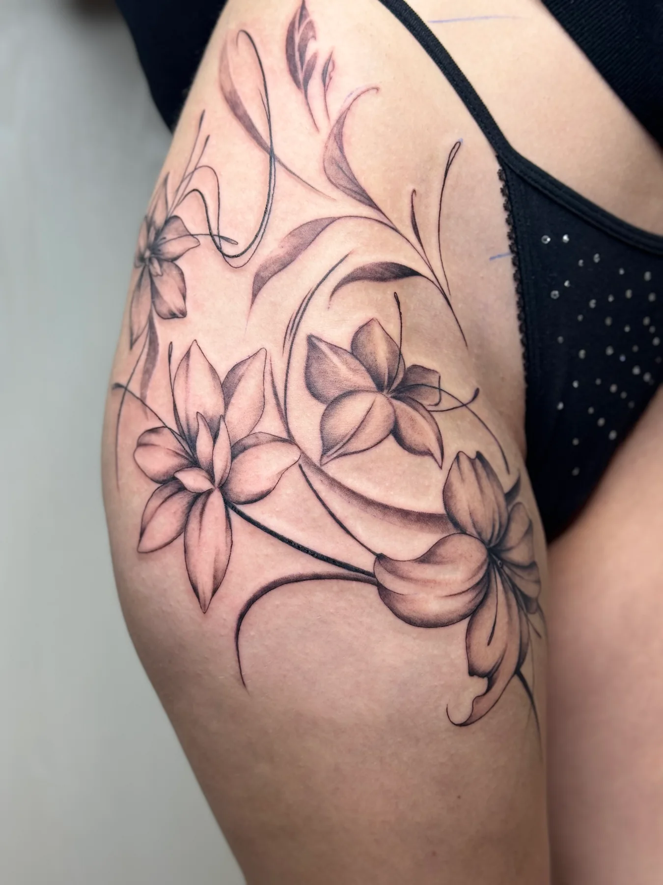 Fine-line floral tattoo across a client's shoulder