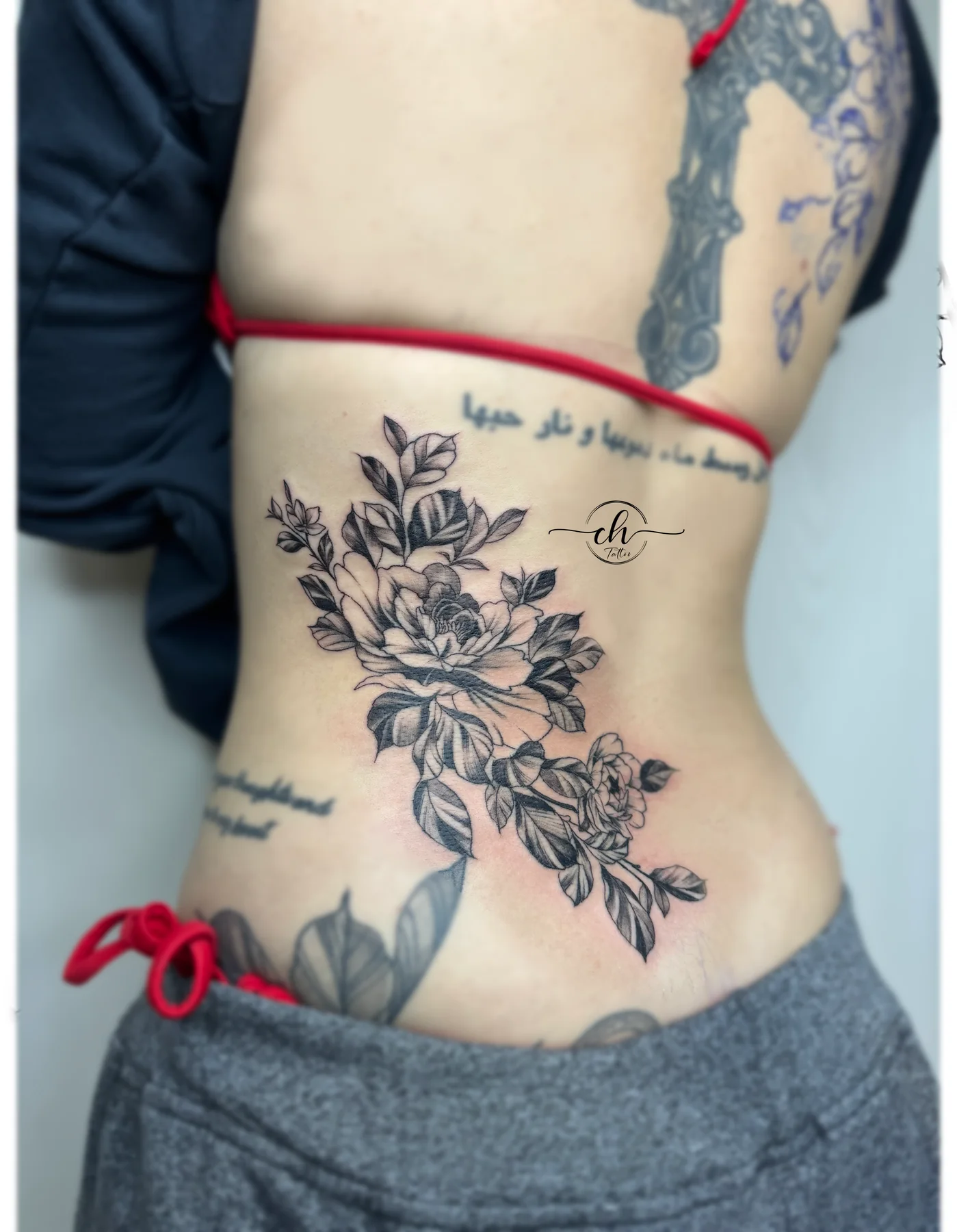 Botanical back tattoo with fine-line script
