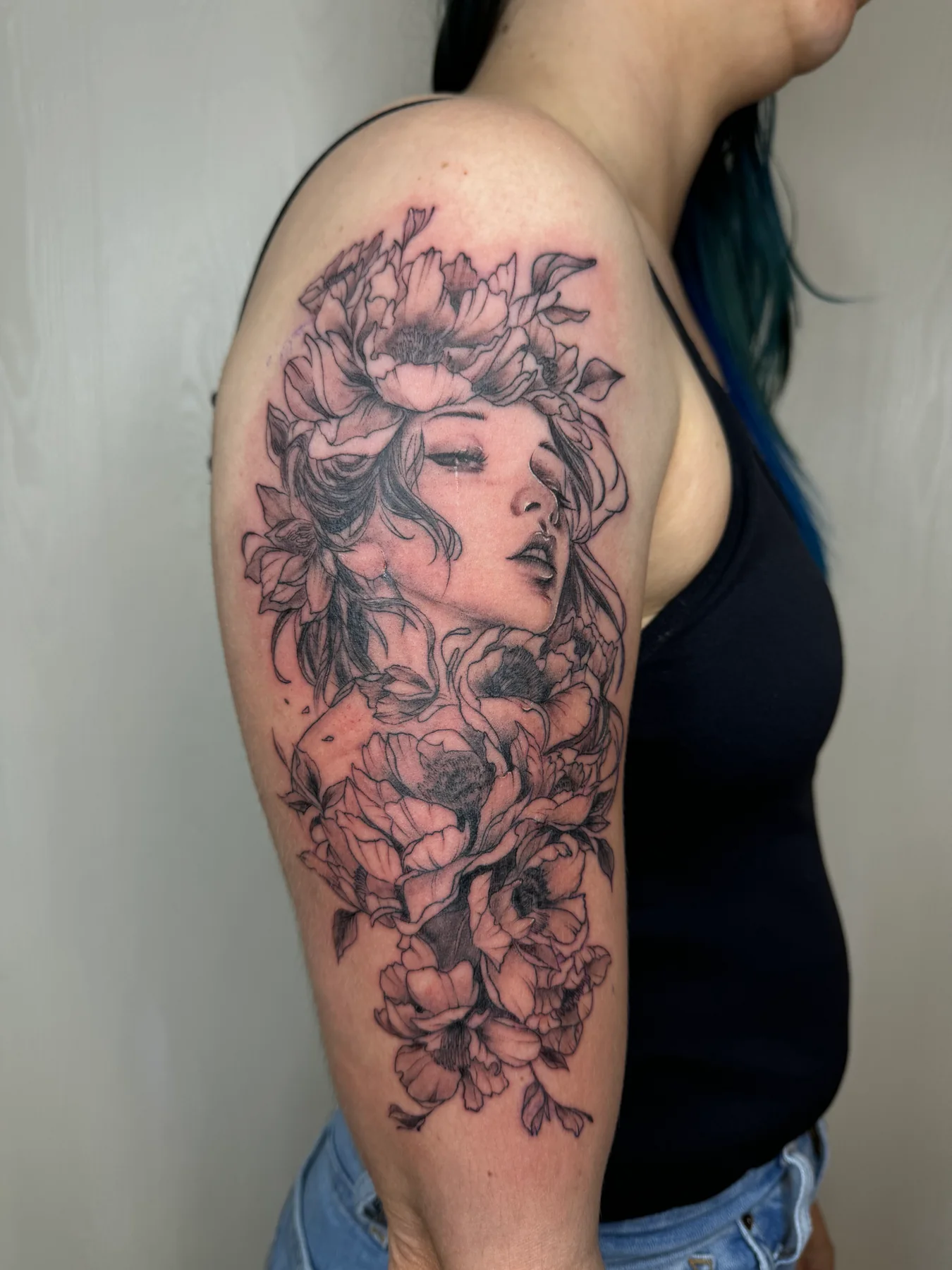 Floral portrait tattoo on a client's upper arm