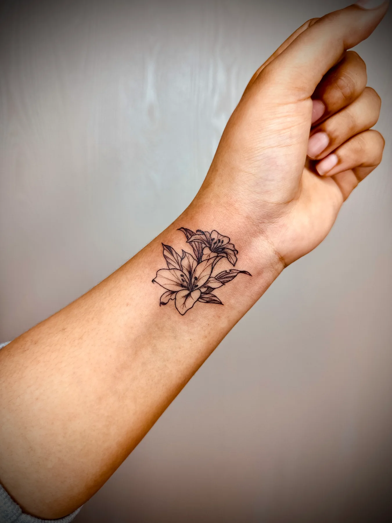 Small fine-line lotus tattoo on a client's wrist
